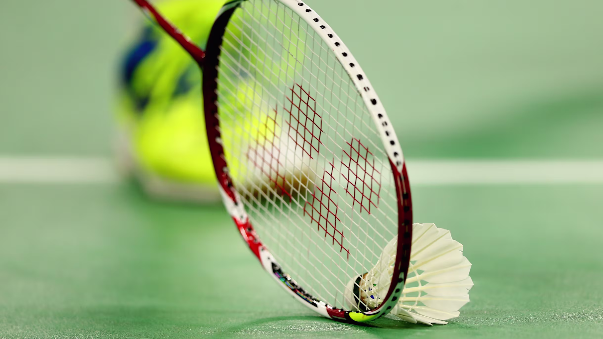 A badminton racket and shuttlecock on court.